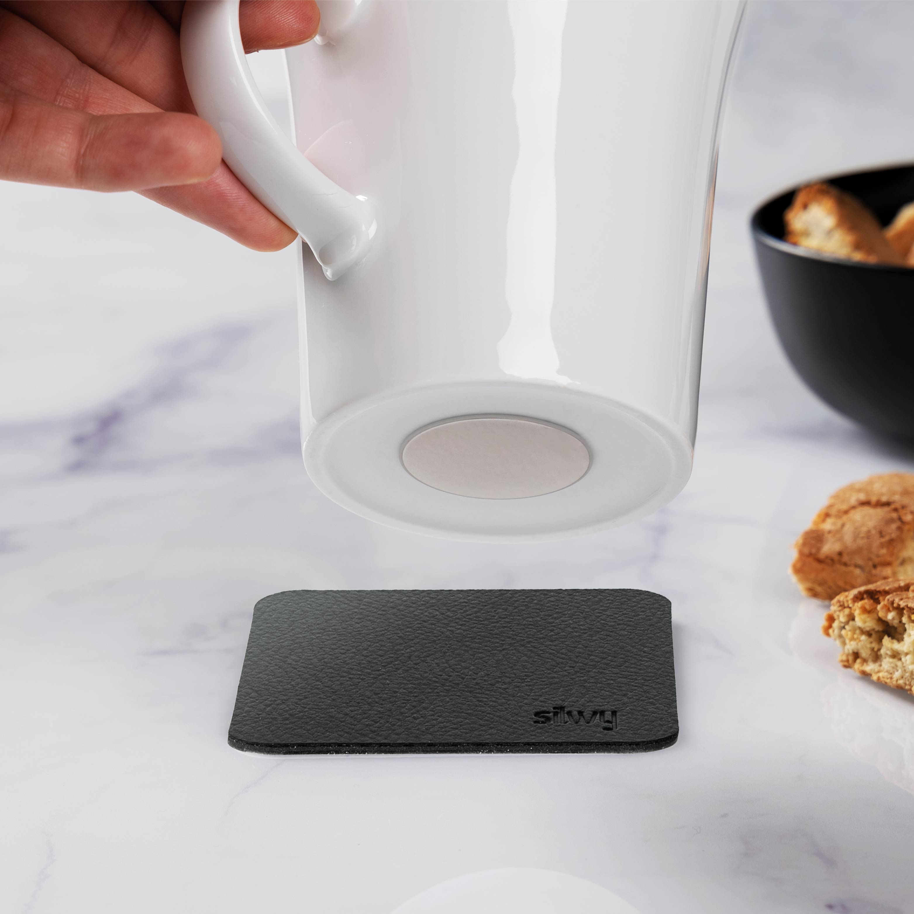 Henkeltasse mit integriertem Magneten im Boden und dem zugehörigen Metall-Nano-Gel-Pad in schwarz