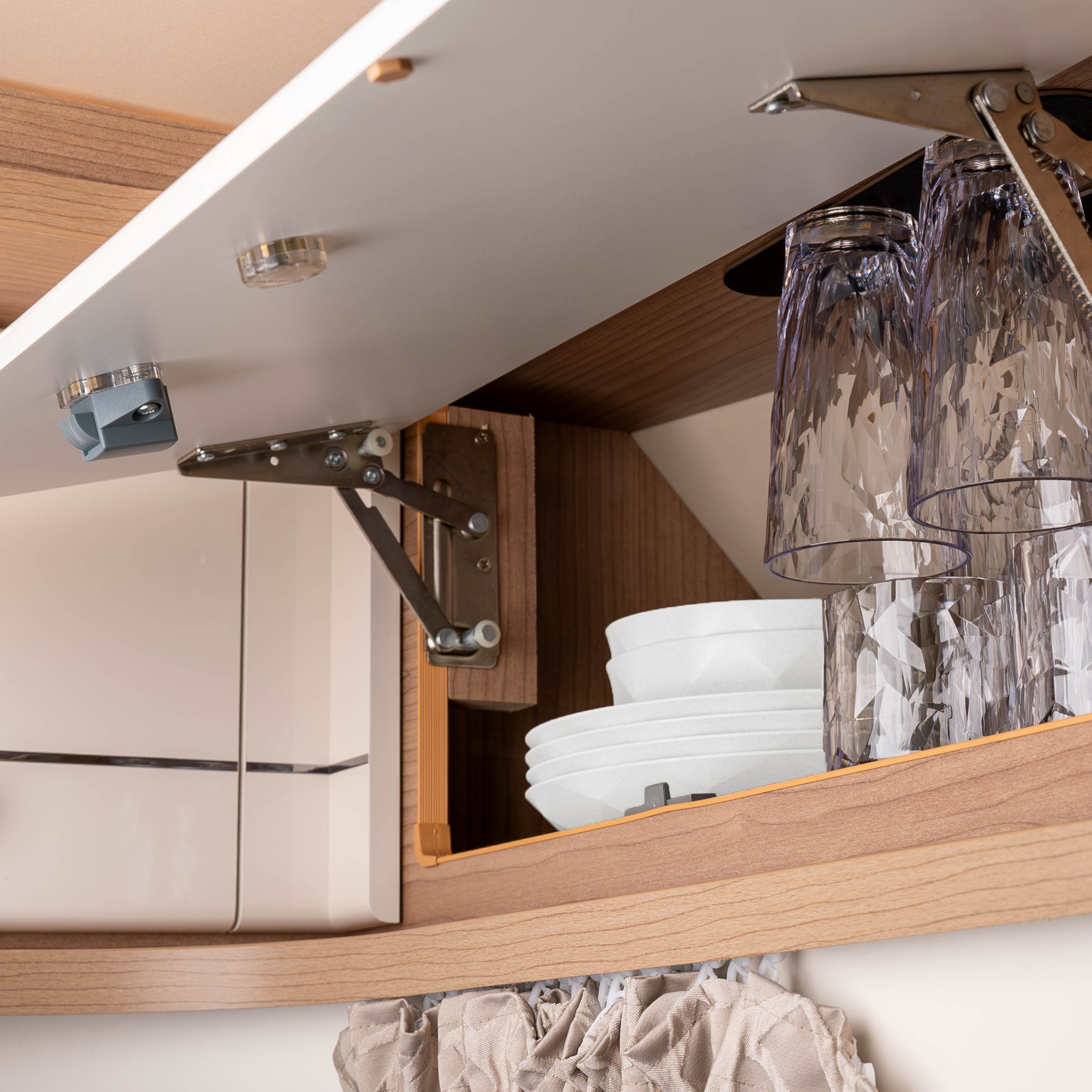 An der Metall-Leiste kopfüber hängende Kunststoffgläser mit Magnet in einem Schrank eines Campers