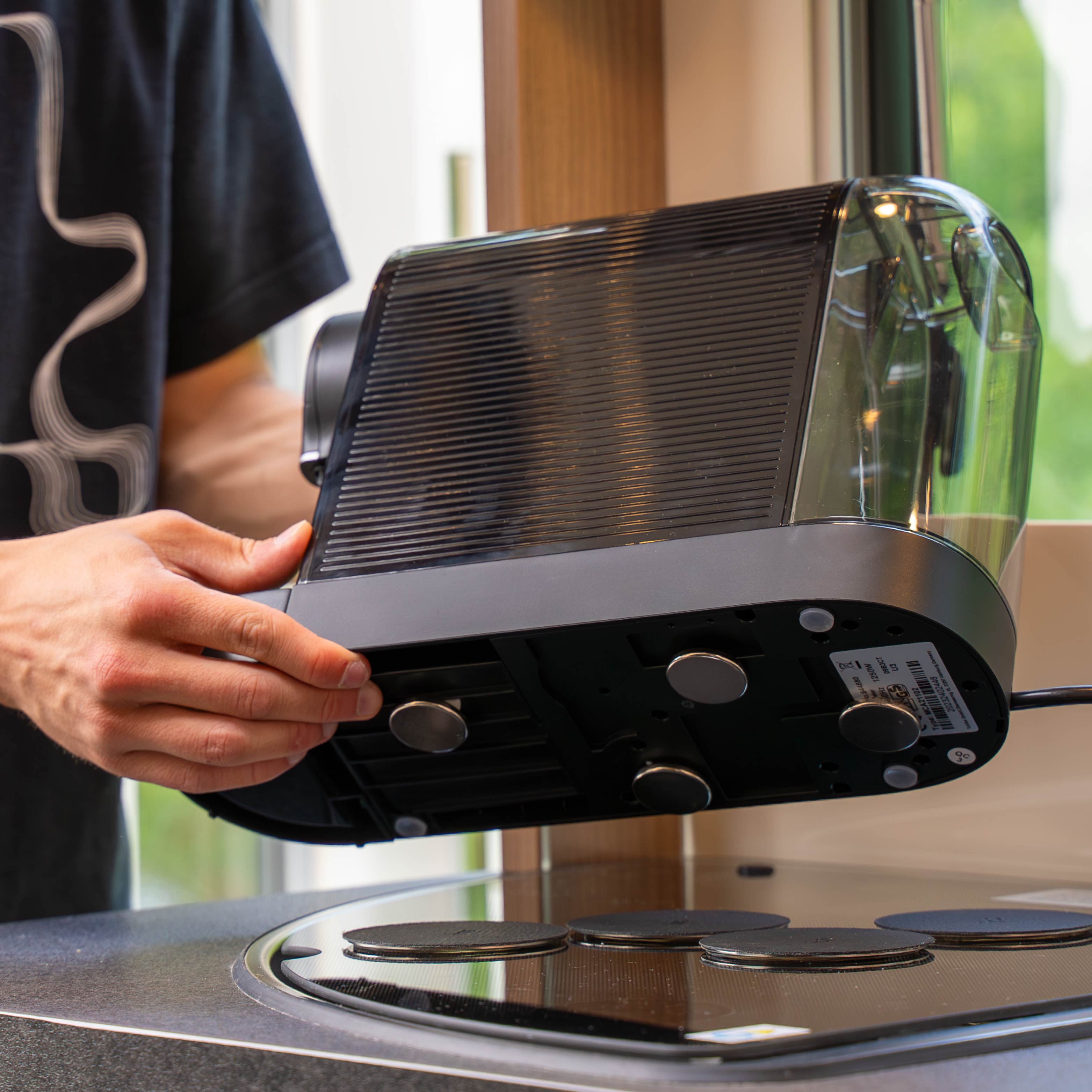 Vier Power-Magnete befestigt an Kaffeemaschine mit den zugehörigen runden, schwarzen Metall-Nano-Gel-Pads