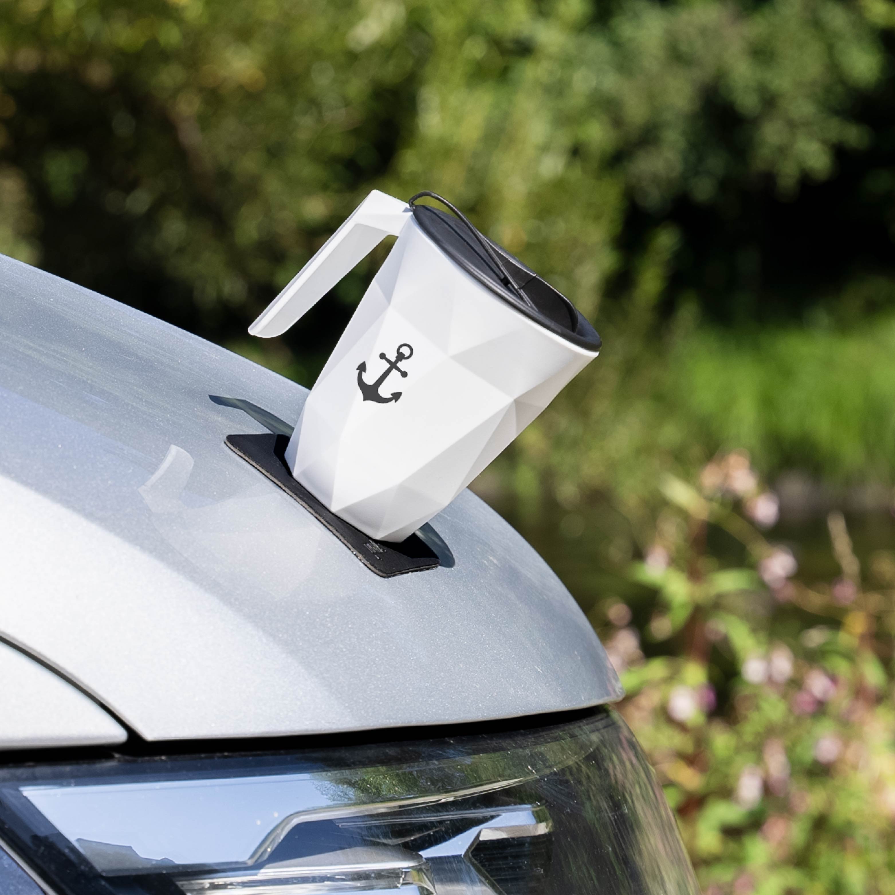 Magnet-Kunststofftasse TO-GO mit Ankersymbol auf einer Seite auf zugehörigem quadratischen Metall-Nano-Gel Pad in schwarz