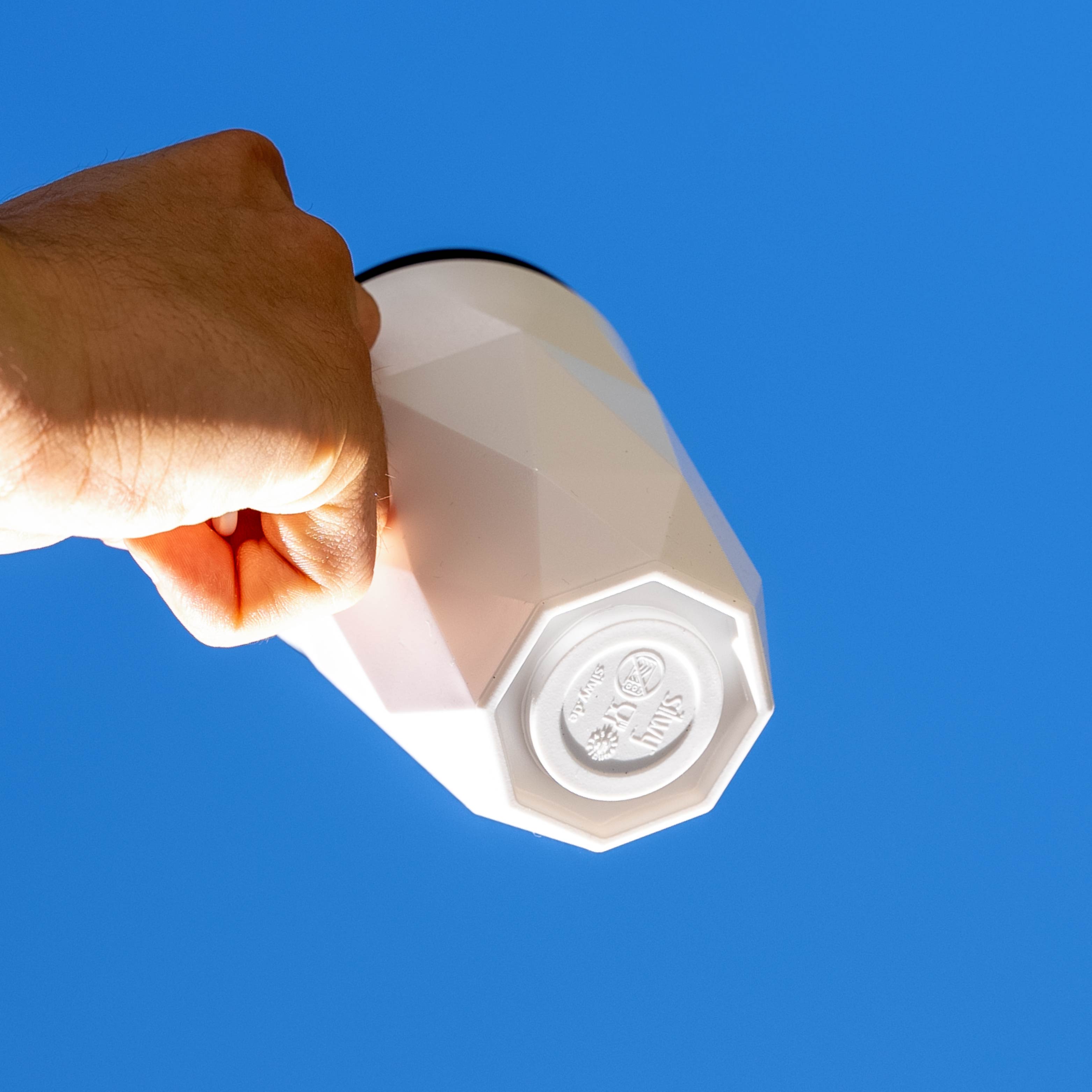 Magnet-Kunststofftasse TO-GO mit integriertem Magnet im Boden vor blauem Hintergrund